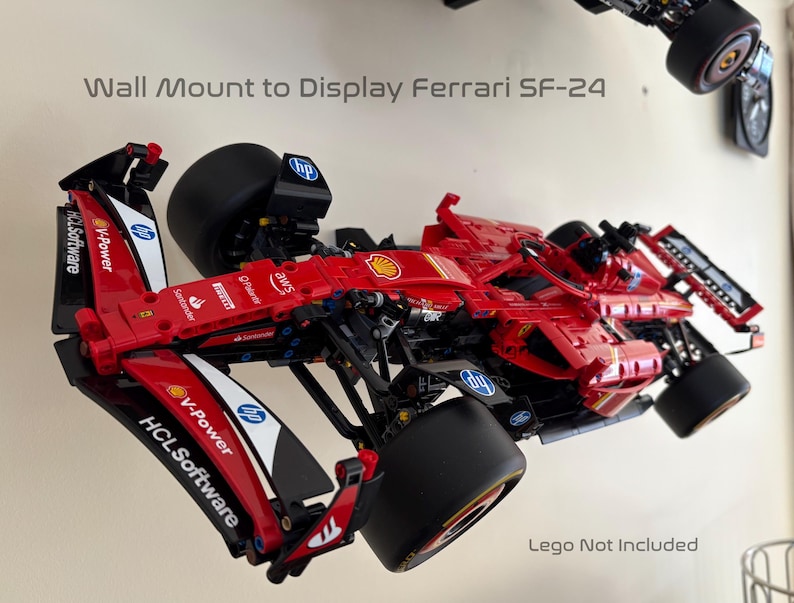 May include: A red, black, and white Lego Ferrari SF-24 race car model mounted on a wall display stand. The car has sponsors' logos including V-Power, HCL Software, and AWS.