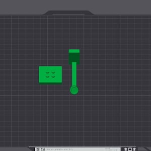 May include: A green 3D printed model of a small building on a dark gray textured surface. The model is made of plastic and has a simple design. The surface is a grid pattern.
