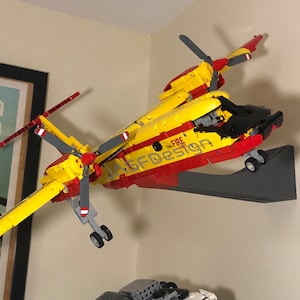 Op de afbeelding: Een geel en rood Lego-model van een brandweer reddingshelikopter met een zwarte cockpit en de woorden "Fire Rescue" en "ASFD Design" gedrukt op de zijkant.