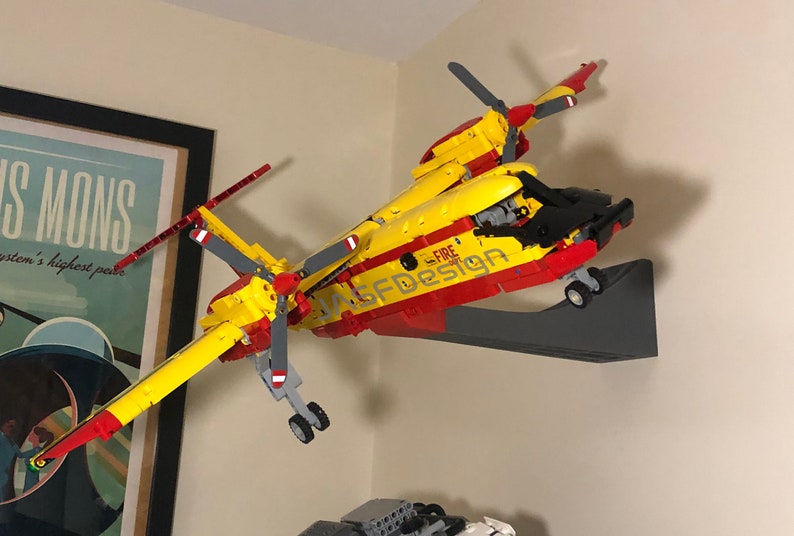 Op de afbeelding: Een geel en rood Lego-model van een brandweer reddingshelikopter met een zwarte cockpit en de woorden "Fire Rescue" en "ASFD Design" gedrukt op de zijkant.