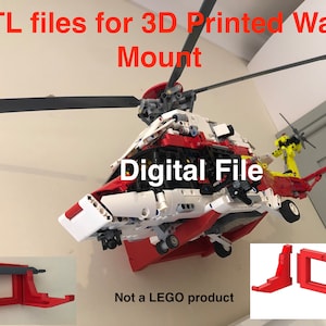 May include: STL files for a 3D printed wall mount for a red, white, and yellow helicopter model. The text "Digital File" is visible on the helicopter. The text "Not a LEGO product" is visible below the helicopter. The image shows two red 3D printed wall mounts.
