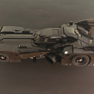 K&ouml;nnte beinhalten: Ein schwarzes Lego Batmobil Modell mit einem detaillierten Design und einer schlanken, aerodynamischen Form. Das Modell verf&uuml;gt &uuml;ber ein Cockpit, R&auml;der und einen Heckspoiler.