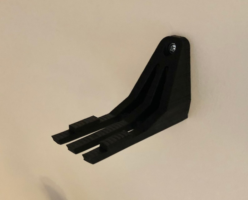 Peut inclure: Support mural en plastique noir avec trois pointes pour accrocher des objets.