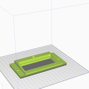 May include: A 3D-rendered, lime green rectangular object with a recessed interior and two circular holes. The object sits on a gray grid, within a white box, suggesting a digital model or prototype.