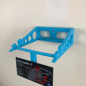 May include: A light blue, 3D-printed shelf with the text "APOLLO LRV" and a sign that reads "NASA Apollo 17". The sign details the forward chassis, power supply, drive control, navigation, high-gain antenna, and special tool.