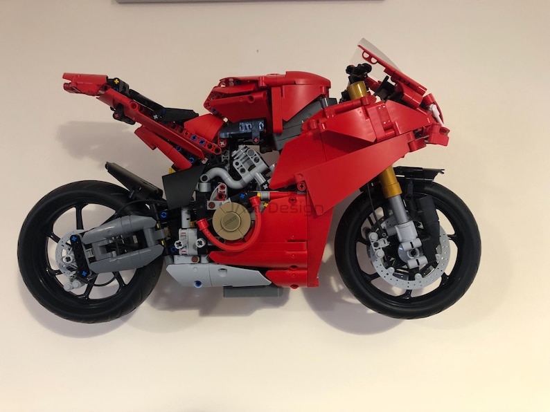 May include: A red and black Lego motorcycle model with a detailed engine and wheels. The motorcycle is built with Lego bricks and is a replica of a real motorcycle.