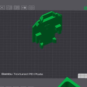 Op de afbeelding: Een groen, geometrisch 3D-model van een Bambu Textured PEI Plate, tegen een donkergrijze rasterachtergrond. De tekst "Bambu Textured PEI Plate" is zichtbaar onderaan de afbeelding. Het model heeft een complex, veelzijdig ontwerp.