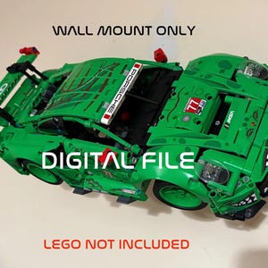 Op de afbeelding: Een groene speelgoed raceauto met rode en witte accenten, met het woord "PORSCHE" en het nummer "77". De tekst "WALL MOUNT ONLY", "DIGITAL FILE" en "LEGO NOT INCLUDED" is ook zichtbaar.