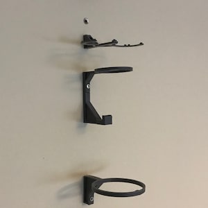 May include: A set of six black wall-mounted hooks for hanging various items. The hooks are made of a sturdy plastic material and are designed to hold a variety of items, such as hats, coats, bags, and other accessories.
