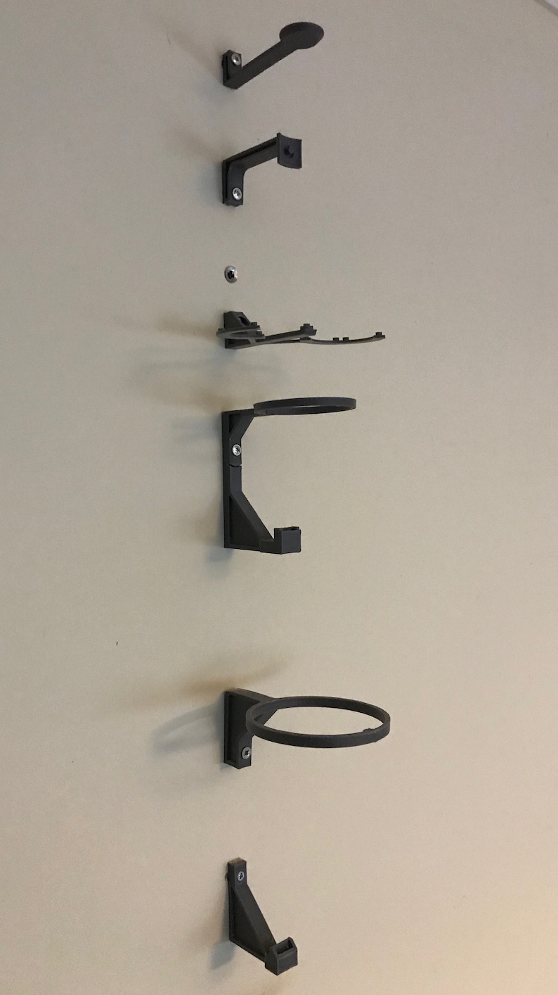 May include: A set of six black wall-mounted hooks for hanging various items. The hooks are made of a sturdy plastic material and are designed to hold a variety of items, such as hats, coats, bags, and other accessories.