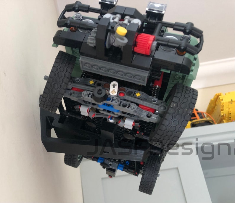 May include: A black and green Lego model of a truck with a detailed engine and suspension. The truck is upside down and the underside is visible.