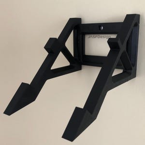May include: Black wall mount for a record player, with a rectangular cutout that says "JASFDesign".