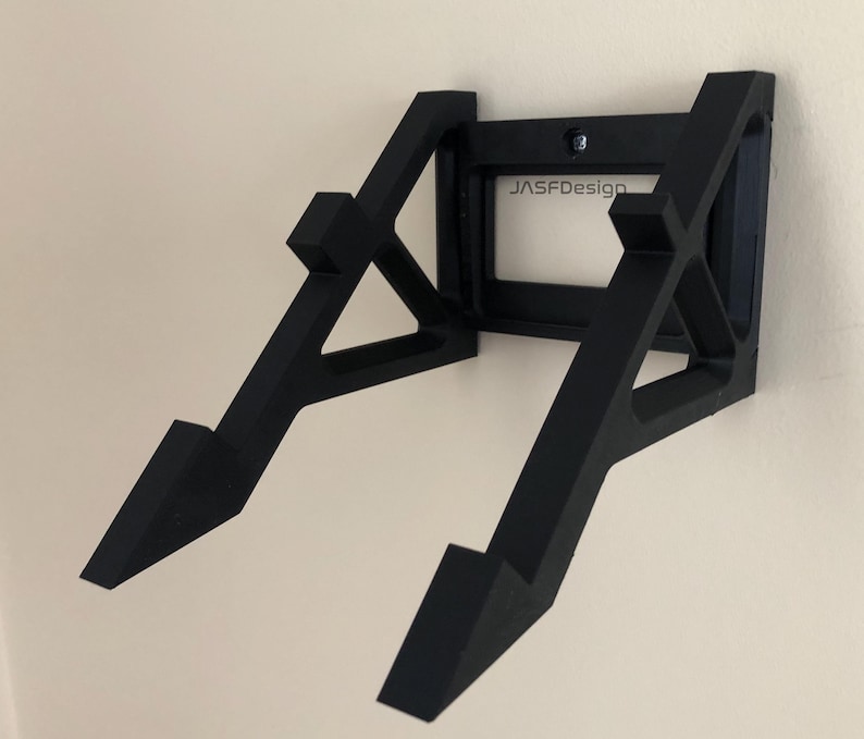 May include: Black wall mount for a record player, with a rectangular cutout that says "JASFDesign".
