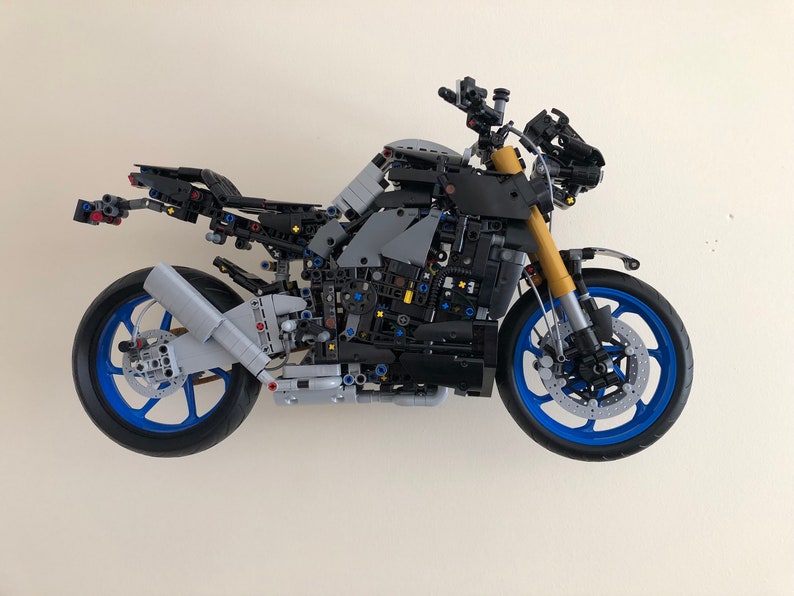 Peut inclure: Un mod&egrave;le de moto Lego noir et gris avec des roues bleues et un moteur d&eacute;taill&eacute;. La moto est construite avec de nombreuses petites pi&egrave;ces et a un design r&eacute;aliste.