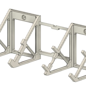 K&ouml;nnte beinhalten: Eine wei&szlig;e Wandhalterung aus Kunststoff f&uuml;r zwei Controller. Die Halterung hat ein geometrisches Design mit einer quadratischen &Ouml;ffnung in der Mitte.