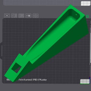 Op de afbeelding: Een felgroen, schuin 3D-geprint object met een lange, trogachtige kanaal en een vierkante opening aan &eacute;&eacute;n uiteinde. Het object staat tegen een donkergrijze rasterachtergrond, met de tekst "textured PEI Plate".