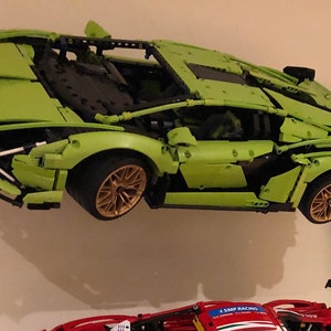 May include: A green Lego Lamborghini Sian FKP 37 model car with black and gold details. The car is suspended in mid-air, as if it is flying.