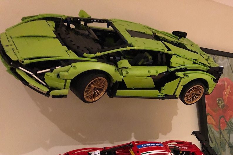 May include: A green Lego Lamborghini Sian FKP 37 model car with black and gold details. The car is suspended in mid-air, as if it is flying.