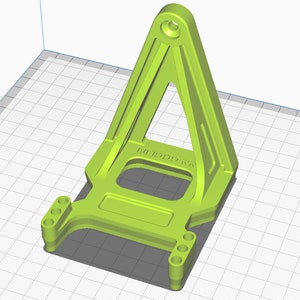 May include: A green plastic 3D printed part with a triangular base and a rectangular platform with four holes on each side. The part has the text "M1 R0000 K1" printed on it.