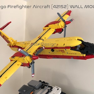 Può includere: Un aereo dei pompieri Lego (42152) giallo e rosso montato a parete. L'aereo ha un muso nero e un cartello rosso e bianco FIRE DEPT sul lato.