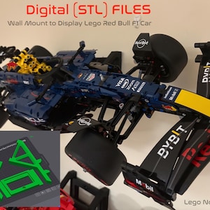 May include: A blue and black Lego Red Bull F1 car mounted on a wall. The car has yellow and red accents, with the words "VISA", "zoom", and "Mobil 1" visible. The image also includes a green 3D model and the text "Digital (STL) FILES".