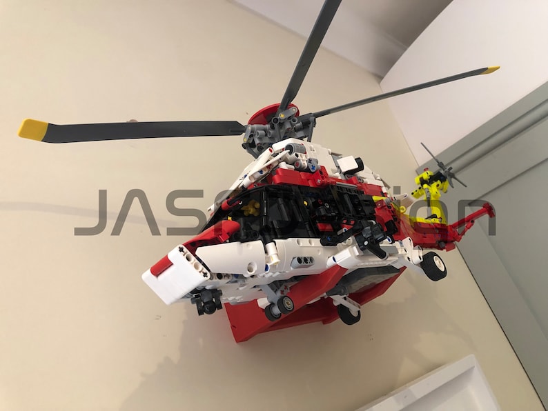 May include: A red, white, and black Lego helicopter model with a yellow rotor blade. The helicopter is mounted on a wall.