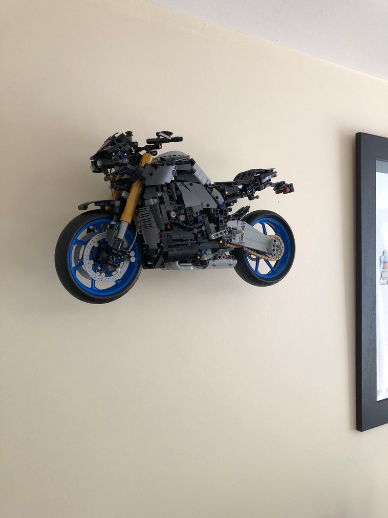 Peut inclure: Un mod&egrave;le de moto LEGO noir et gris avec des roues bleues. La moto est mont&eacute;e sur un mur.