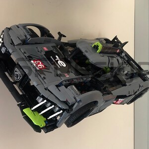 May include: A grey and green model race car with the number 66 and the text "TE" on the side. The car has a detailed interior and a spoiler on the back.