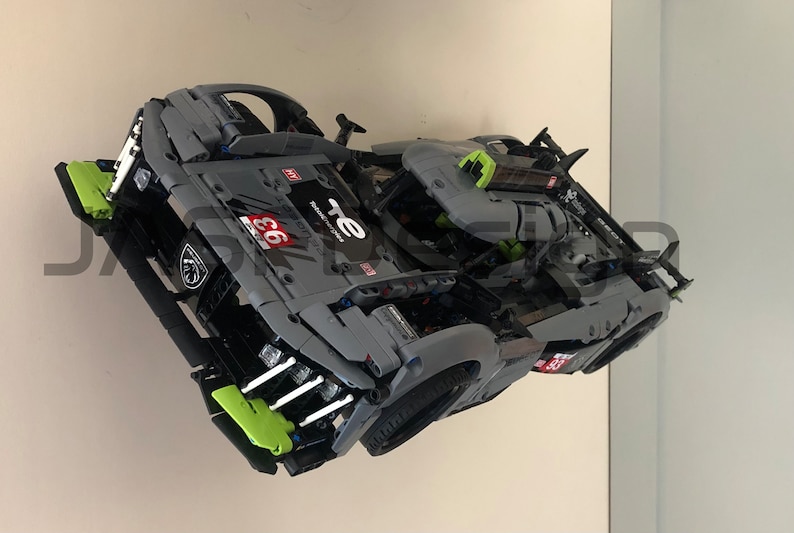 May include: A grey and green model race car with the number 66 and the text "TE" on the side. The car has a detailed interior and a spoiler on the back.
