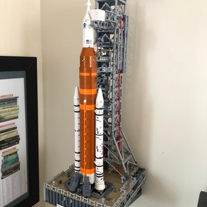 May include: A wall mount system for a Lego space shuttle model. The system is made of gray metal and has a platform for the shuttle to sit on. The shuttle is not included.