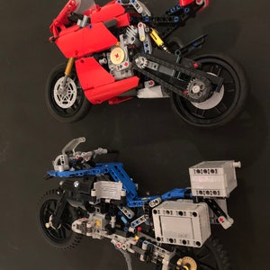 May include: Two detailed Lego motorcycle models, one red and one blue, with intricate details and working parts. The red motorcycle is a sport bike, while the blue motorcycle is a dirt bike.