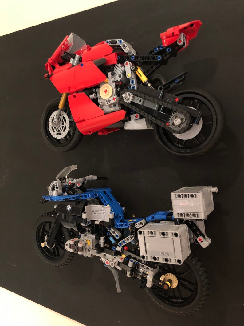 May include: Two detailed Lego motorcycle models, one red and one blue, with intricate details and working parts. The red motorcycle is a sport bike, while the blue motorcycle is a dirt bike.