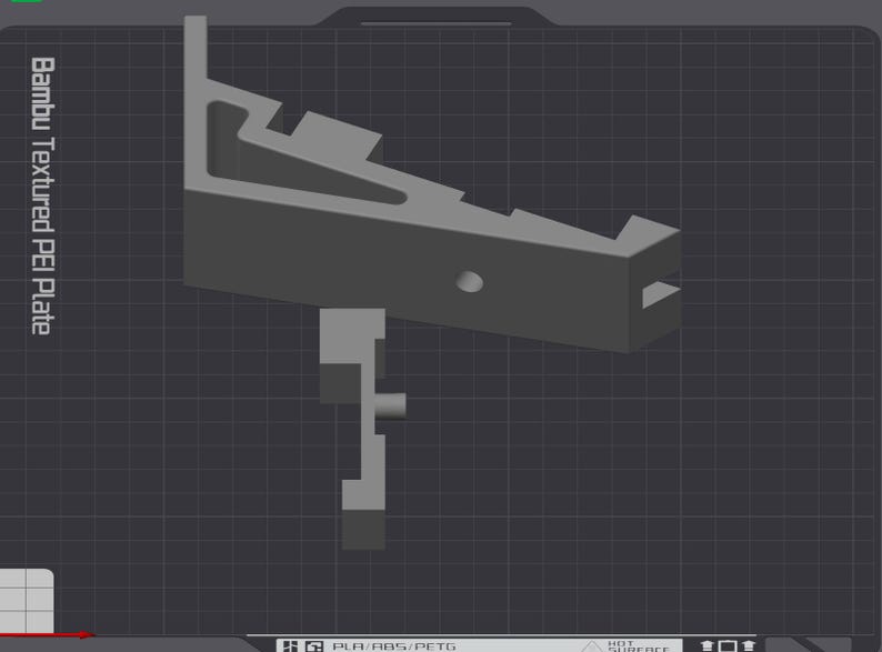 Puede incluir: Una pieza gris impresa en 3D con una superficie texturizada. La pieza est&aacute; dise&ntilde;ada para ser utilizada con una impresora 3D. El texto "Bambu Textured PEI Plate" es visible en el lado izquierdo de la imagen.