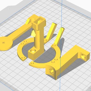 May include: A collection of yellow 3D-printed parts, including a lever with a circular end, a U-shaped piece, and a right-angled component. The parts are arranged on a grid background, showcasing their geometric designs.