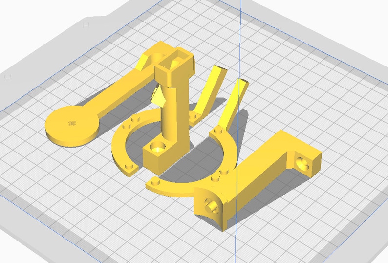 May include: A collection of yellow 3D-printed parts, including a lever with a circular end, a U-shaped piece, and a right-angled component. The parts are arranged on a grid background, showcasing their geometric designs.