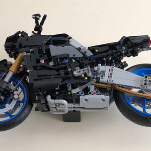 Peut inclure: Mod&egrave;le de moto Lego noir et bleu avec une cha&icirc;ne dor&eacute;e et un moteur d&eacute;taill&eacute;. La moto est construite avec de nombreuses petites pi&egrave;ces et a un design r&eacute;aliste.
