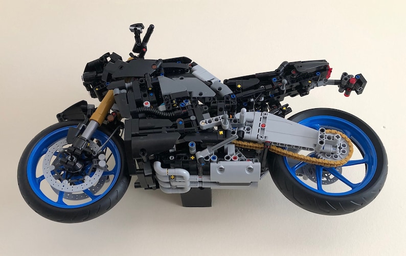 Peut inclure: Mod&egrave;le de moto Lego noir et bleu avec une cha&icirc;ne dor&eacute;e et un moteur d&eacute;taill&eacute;. La moto est construite avec de nombreuses petites pi&egrave;ces et a un design r&eacute;aliste.