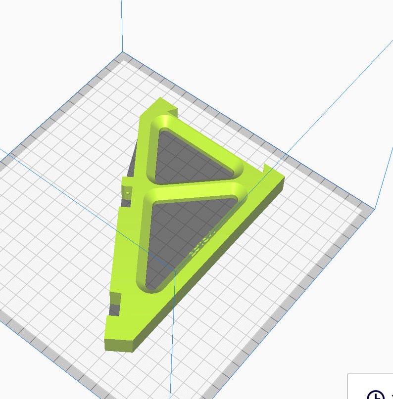 May include: A bright green, triangular 3D-printed object with a hollow interior and rounded edges. The object sits on a gray grid, suggesting a design or modeling environment. The design features a central triangular opening.