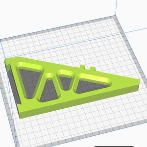 Puede incluir: Un objeto triangular impreso en 3D de color verde brillante con varios recortes geom&eacute;tricos. El objeto tiene una base plana y una serie de aberturas triangulares y redondeadas. El dise&ntilde;o sugiere un componente estructural o mec&aacute;nico.