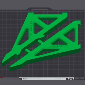 Puede incluir: Dos objetos impresos en 3D de pl&aacute;stico verde sobre un fondo de cuadr&iacute;cula negra. Los objetos tienen forma de tri&aacute;ngulos con una superficie texturizada. El texto "BAMBU TEXTURED PEI PLATE" es visible en el lado izquierdo de la imagen.