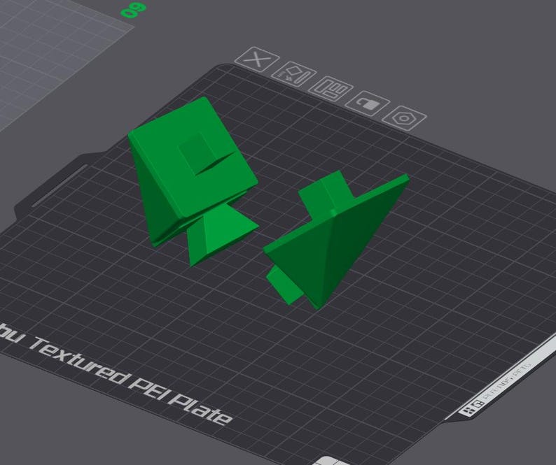 K&ouml;nnte beinhalten: Zwei gr&uuml;n bedruckte 3D-Objekte auf einer strukturierten schwarzen Oberfl&auml;che. Die Objekte sind geometrische Formen mit scharfen Kanten.