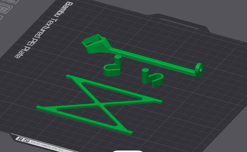 Peut inclure: Un mod&egrave;le d'une chaise imprim&eacute; en 3D en vert avec une poign&eacute;e s&eacute;par&eacute;e imprim&eacute;e en 3D en vert. Le mod&egrave;le est sur une surface textur&eacute;e noire avec le texte "Bambu Textured PEI Plate".