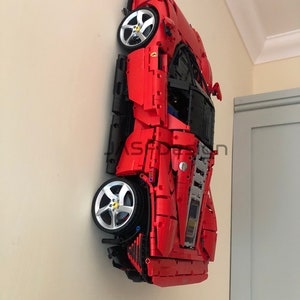 May include: A red and black Lego model of a Ferrari sports car, mounted on a wall.