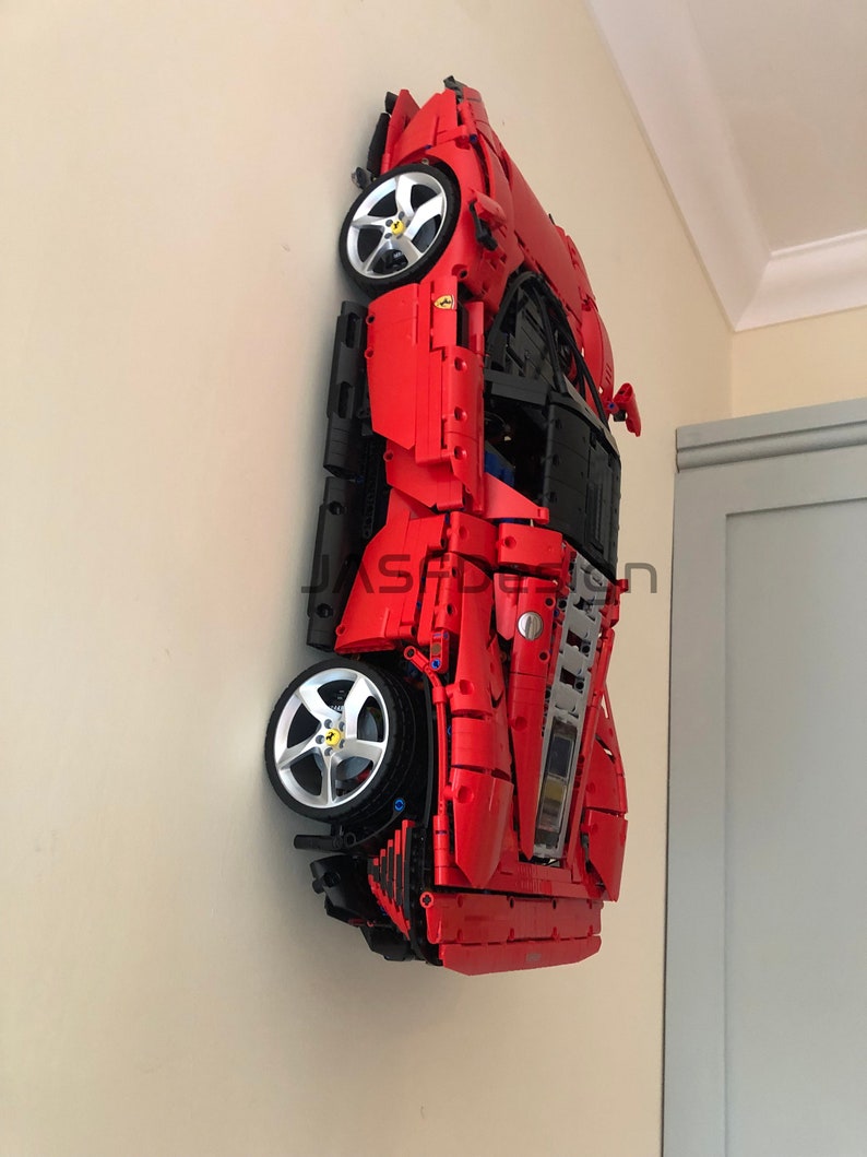 May include: A red and black Lego model of a Ferrari sports car, mounted on a wall.