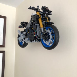 Peut inclure: Un mod&egrave;le de moto Lego noir et bleu avec des accents jaunes est mont&eacute; sur un mur.