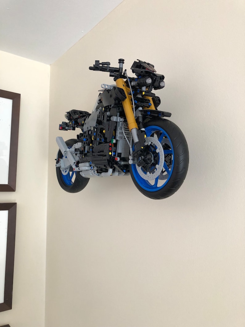 Peut inclure: Un mod&egrave;le de moto Lego noir et bleu avec des accents jaunes est mont&eacute; sur un mur.