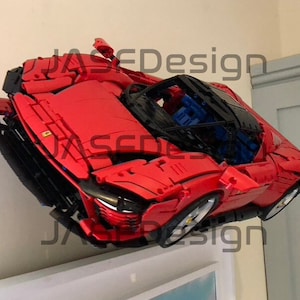 May include: A red Lego Ferrari model car with black accents and a blue interior. The car is mounted on a wall and appears to be floating.