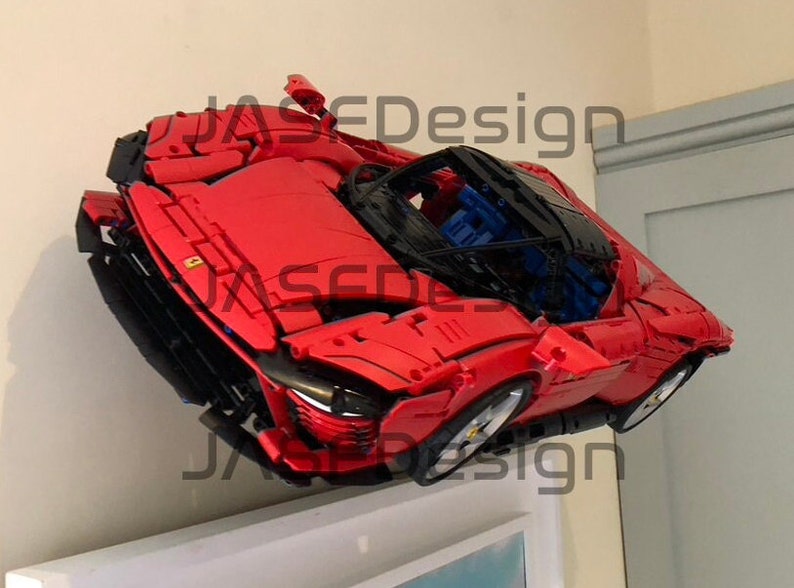 May include: A red Lego Ferrari model car with black accents and a blue interior. The car is mounted on a wall and appears to be floating.