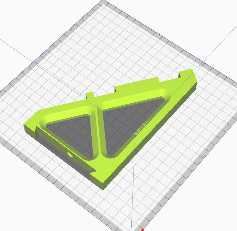 May include: A bright lime green 3D-printed object with a geometric design. The object features two triangular cutouts and a rectangular base. The design includes a small circular hole and text on the side. The object is set against a grid background.