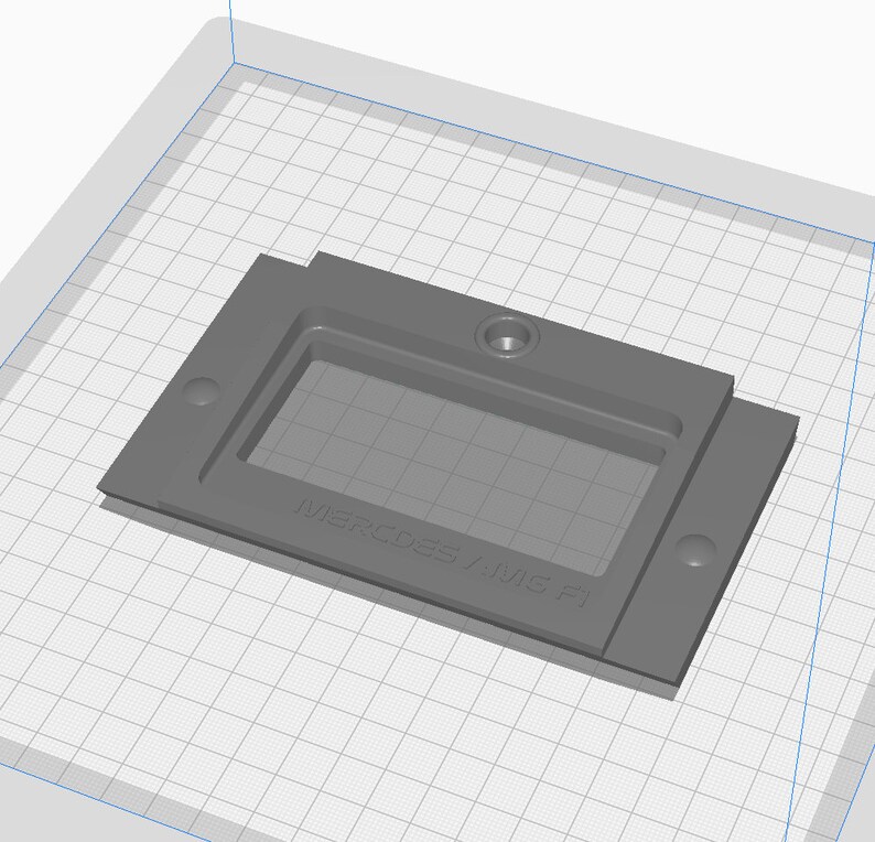 May include: Gray plastic mold with a rectangular cutout and the text "Mercedes-AMG F1" on the bottom.